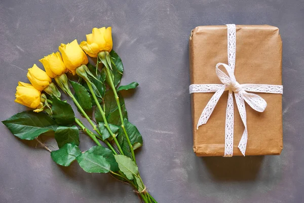 Žluté růže kytice a box dárek na šedém pozadí — Stock fotografie