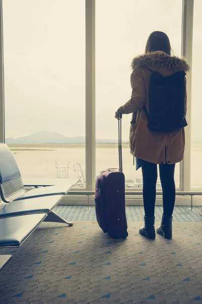 Havaalanında, pencereden uçaklara bakan genç bir kadın. — Stok fotoğraf
