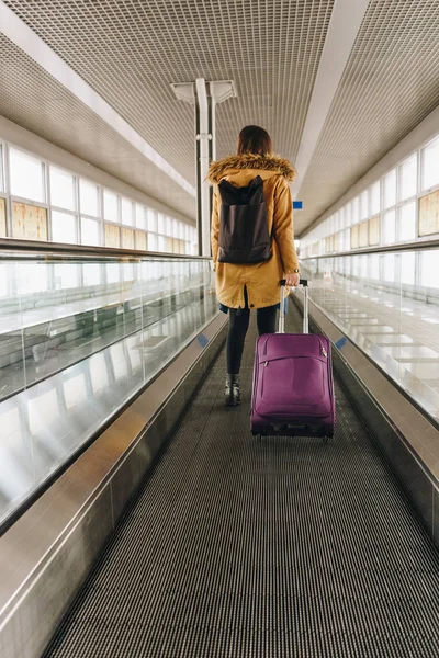 Młoda kobieta z bagażu podręcznego na chodnikiem o międzynarodowych — Zdjęcie stockowe