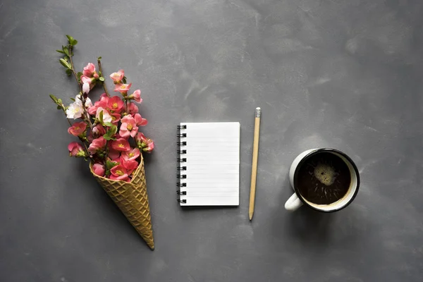 Flowers in ice cream cone and coffee on cement background — Stock Photo, Image