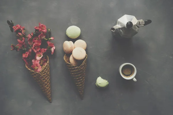 Café, macarrones y flores en cono de helado sobre fondo de cemento —  Fotos de Stock