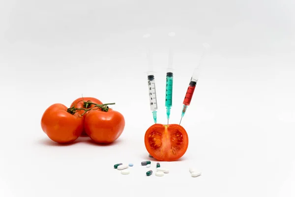 Concept OGM sur fond blanc avec seringues, pilules et tomate — Photo