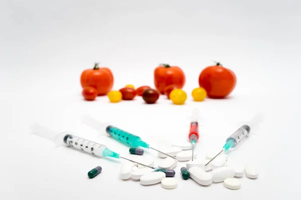 Concetto di OGM su sfondo bianco con siringhe, pillole e tomat — Foto Stock