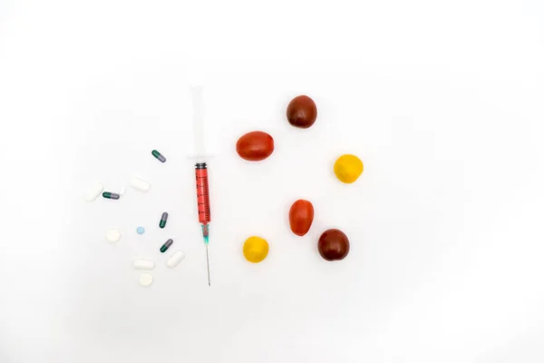 GMO concept on white background with  syringes, pills  and tomat — Stock Photo, Image
