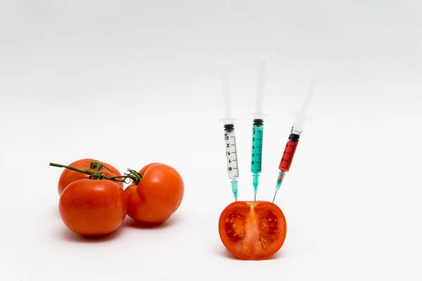 Concepto de OMG sobre fondo blanco con jeringas y tomates . — Foto de Stock