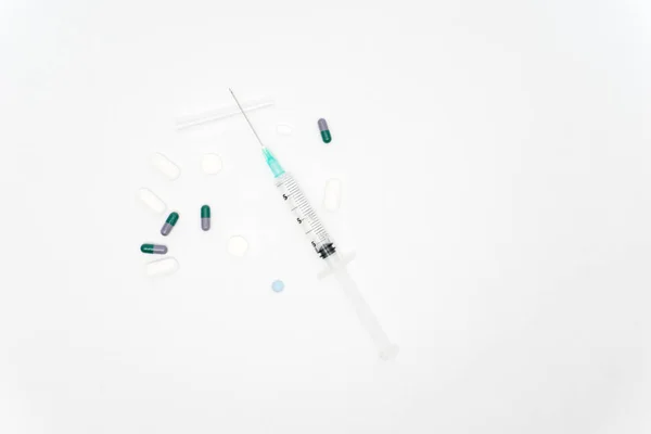 Ιατρική σύριγγα και τα χάπια που απομονώνονται σε λευκό φόντο — Φωτογραφία Αρχείου