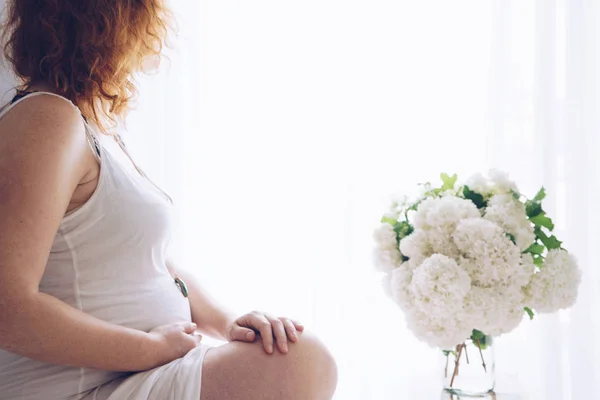 Junge schöne schwangere Frau sitzt am Fenster zu Hause — Stockfoto