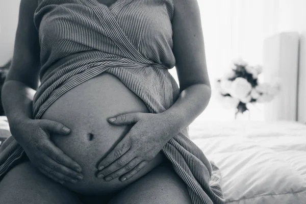 Nahaufnahme einer schwangeren Frau, die ihren Bauch mit den Händen berührt — Stockfoto