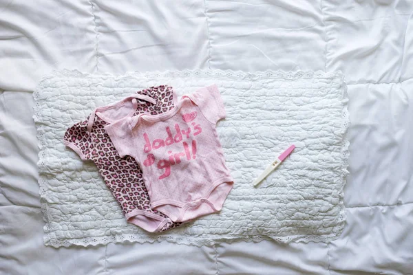 Nyfödd baby girl kläder och graviditetstest på vit bakgrund — Stockfoto