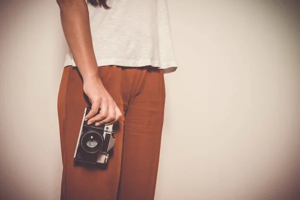 Woman holding a vintage camera front a white background