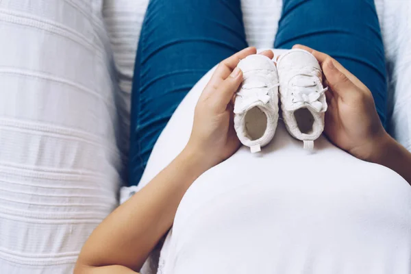 Terhes nő baba cipő tartja a kezében, felülnézet — Stock Fotó