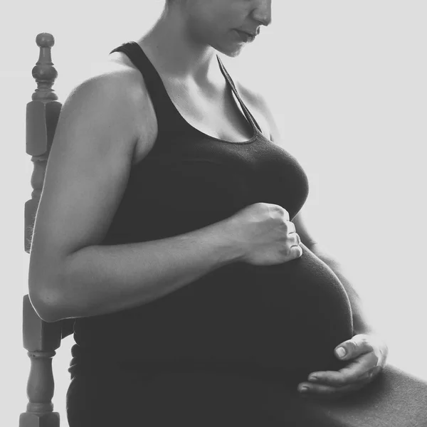 Mooie jonge zwangere vrouw zitten bij het raam in kamer — Stockfoto