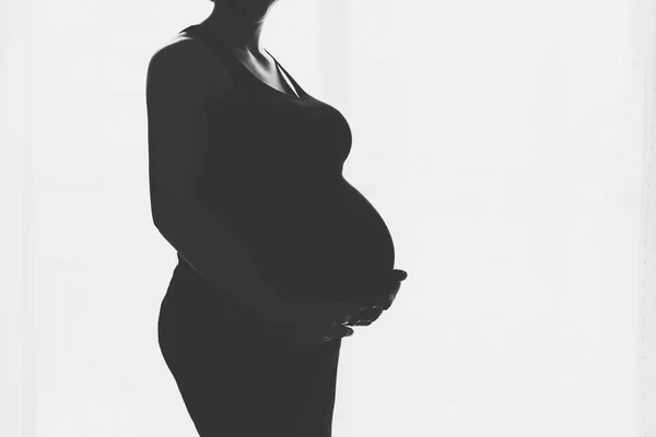 Mujer embarazada de pie contra la ventana —  Fotos de Stock