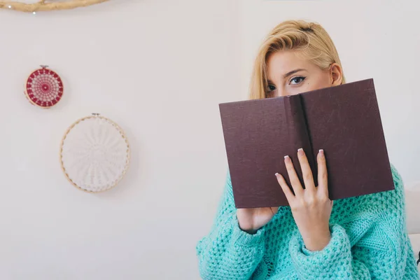 Yatakta kitap okurken oturan genç kadın