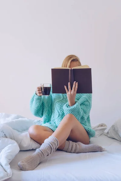 Yatakta kitap okurken oturan genç kadın