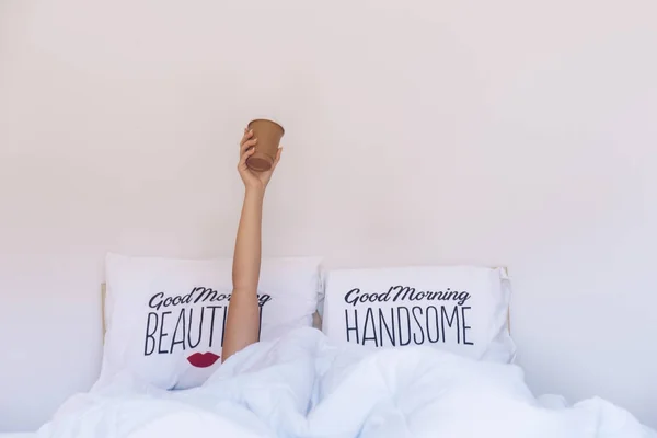 Жінка під ковдрою на ліжку тримає чашку кави — стокове фото