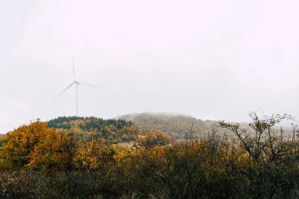 Wind power generator in berg met mist — Stockfoto