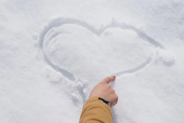 Γυναίκα πλησιάζει μια καρδιά στο χιόνι — Φωτογραφία Αρχείου