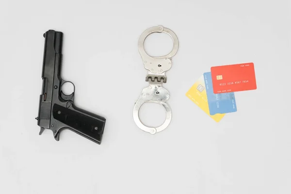 Χειροπέδες, όπλο και πιστωτικές κάρτες σε λευκό φόντο — Φωτογραφία Αρχείου