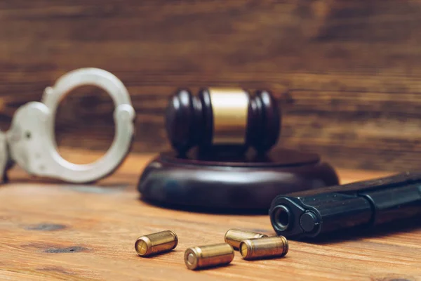 Giudice martelletto, pistola e manette su fondo di legno — Foto Stock