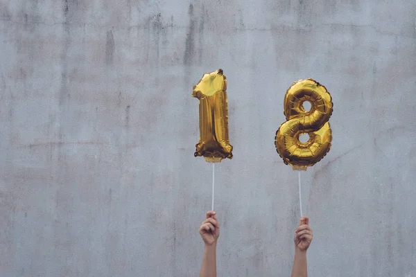 Hände halten goldene 18 Luftballons, Neujahrskonzept lizenzfreie Stockbilder