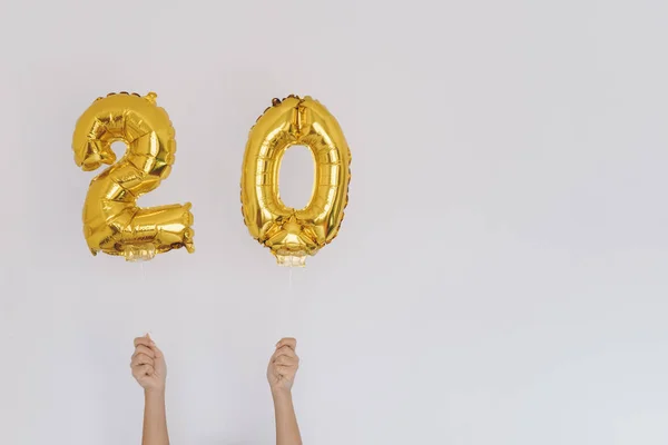 Manos sosteniendo globos dorados 20, concepto de cumpleaños Imagen de archivo