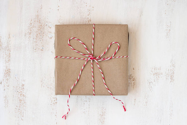 Винтажная подарочная коробка ручной работы с красной веревкой на белой деревянной доске
