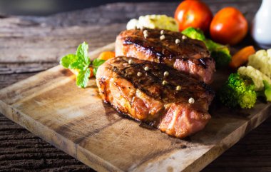 ahşap tahta üzerinde sebzeli ızgara domuz biftek servis