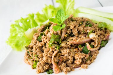 Tay yemeği. larb moo Tay adı. Beyaz ahşap tahta üzerinde otlar ile baharatlı domuz salatası