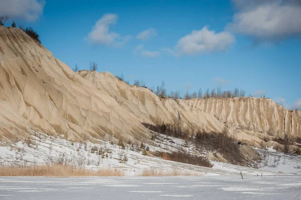 Old slag heap in the background of a blue sky with clouds. Winter season. Rummu, Estonia. Lip of a quarry