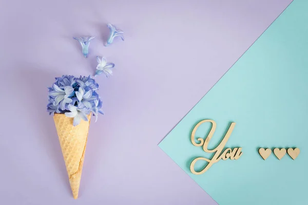 Ice cream horn or cone with purple hyacinth on a purple -mint background.  Declaration of Love to You.  Floral minimalism, greeting card with envelope. Top view, place for text.