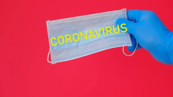 Elinde Coronavirus yazılı tıbbi bir maske var.