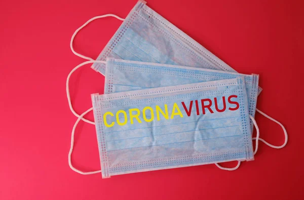 Blue medical mask on a red background with the word coronavirus — Stock Photo, Image