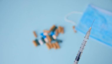 Bulanık arka plan hapları ve tıbbi maskeler üzerindeki şırınga