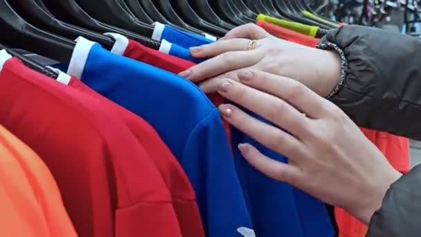 Op zoek naar t-shirts op een hanger in een winkel — Stockvideo