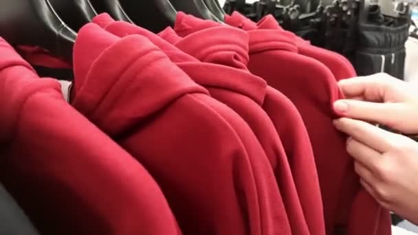 Alla ricerca di t-shirt su una gruccia in un negozio — Video Stock