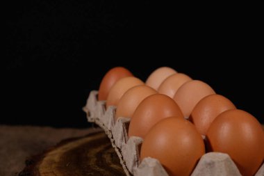 Karton bir kutuda bir düzine yumurta, siyah bir arka plan görünümünde..