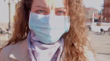 Tıbbi maskeli kıvırcık kız ağır çekimde gider.