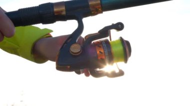 Bir kadının eli oltayla oltayı bir makaraya çevirir..