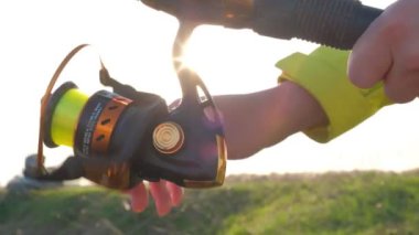 Bir kadının eli oltayla oltayı bir makaraya çevirir..