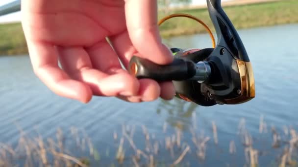 A woman's hand turns a reel with a fishing line on a fishing rod. — Stock Video