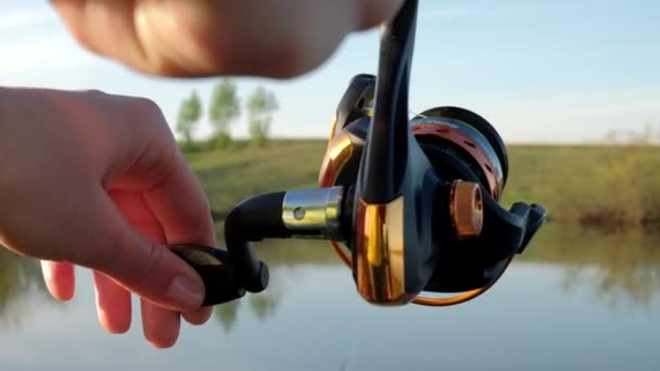 La mano di una donna gira una bobina con una lenza su una canna da pesca . — Video Stock