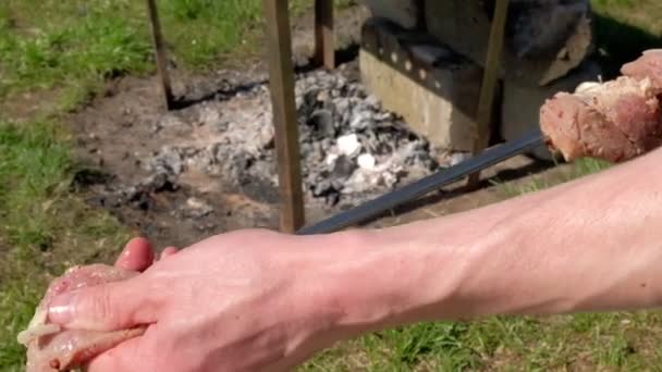Человек, держащий сырое мясо на шампуре — стоковое видео