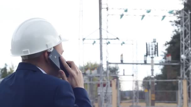 Boos ingenieur schreeuwen, praten over de telefoon tegen de achtergrond van een elektriciteitscentrale — Stockvideo