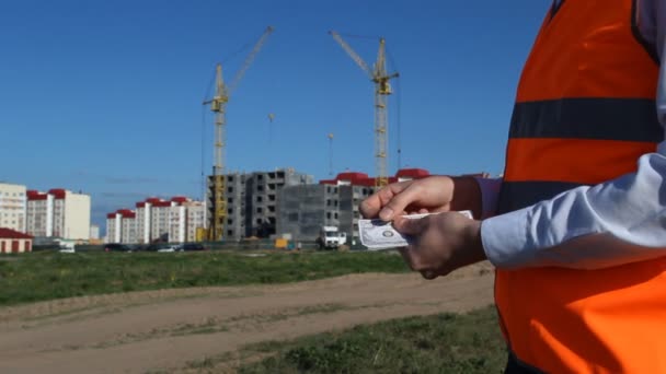A fej számít pénz dollárt, a háttérben egy apartman ház építése — Stock videók
