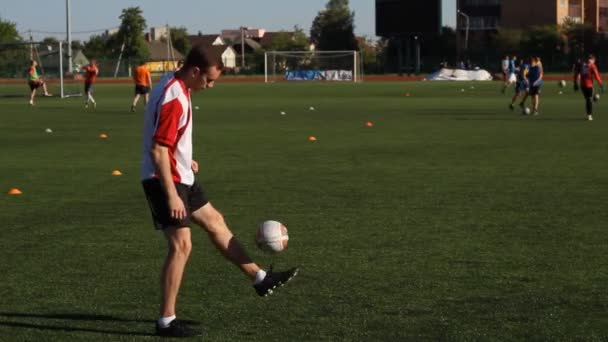 Футболист тренируется и прыгает футбольным мячом по ноге — стоковое видео