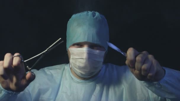 Dokter met tang of grijper en scalpel kijkt naar de camera en klaar om te beginnen met het snijden van een patiënt weefsels in het ziekenhuis. Operatie en operatietafel concept — Stockvideo