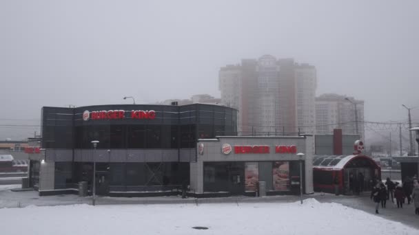 Burger King gyorsétterem hóvihar idején rossz idő télen. Minszk, Fehéroroszország 12.21.18. Épület kint. Az emberek ki-be járkálnak a metró aluljárójából. Kézi lövés. — Stock videók