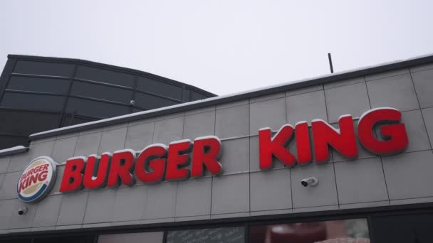 Closeup signboard Fast food restaurant Burger King in MINSK, BELARUS 12.21.18. Blizzard bad weather in winter. Building outside. Handheld shot — Stock Video