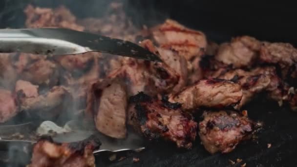Chef takes ready-fried pieces of meat from bbq grill in slow motion. Food and Catering. Traditional national marinated dish Shashlik or shish kebab is fried on barbecue. Close up — ストック動画